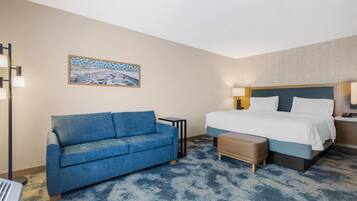 Una camera d'albergo con un letto, un divano blu, un tavolino e un quadro appeso al muro.