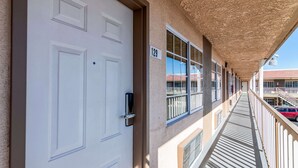 A corridor with a white door, a balcony with a railing, and a building number sign. - Rodeway Inn Barstow Route 66 (Barstow)