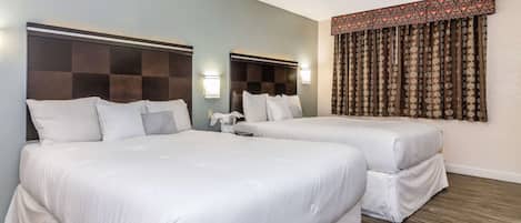 Habitación de hotel con dos camas, cabecera a cuadros, luces fijadas a la pared y cortina estampada.