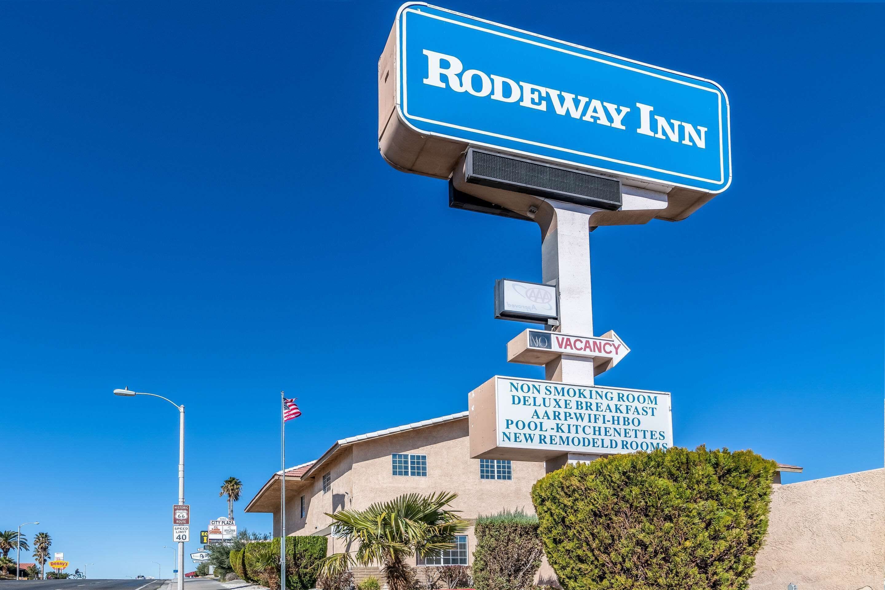 Une enseigne pour le Rodeway Inn, indiquant la présence d'un espace non-fumeur, d'un petit-déjeuner amélioré, d'un petit-déjeuner proposé aux membres de l'AARP, d'une piscine, de petites cuisines et de chambres récemment rénovées.