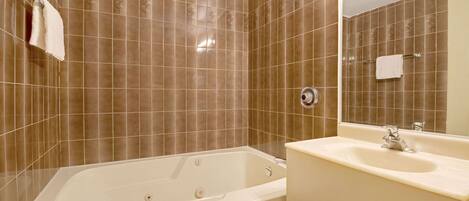 Un baño con bañera, lavabo y espejo.