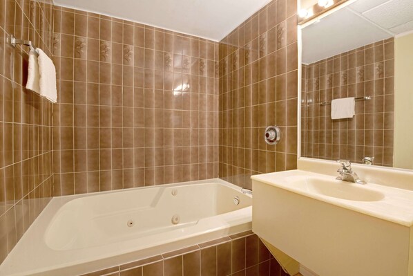 A bathroom with a bathtub, sink, and mirror.