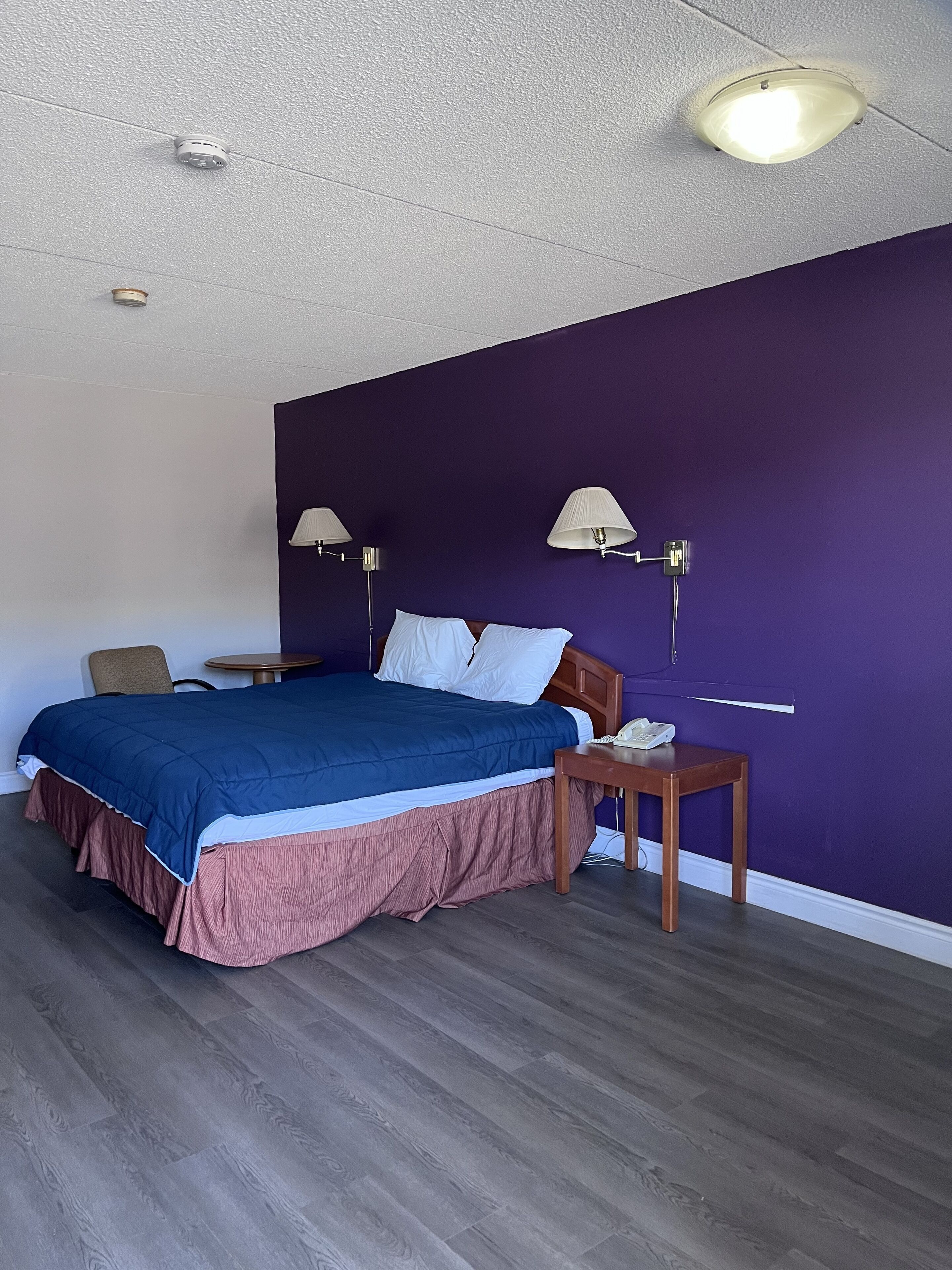 Un dormitorio con cama, mesitas de noche, lámpara y luz de techo.