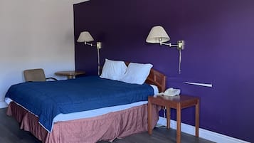 Un dormitorio con cama, mesitas de noche, lámpara y luz de techo.