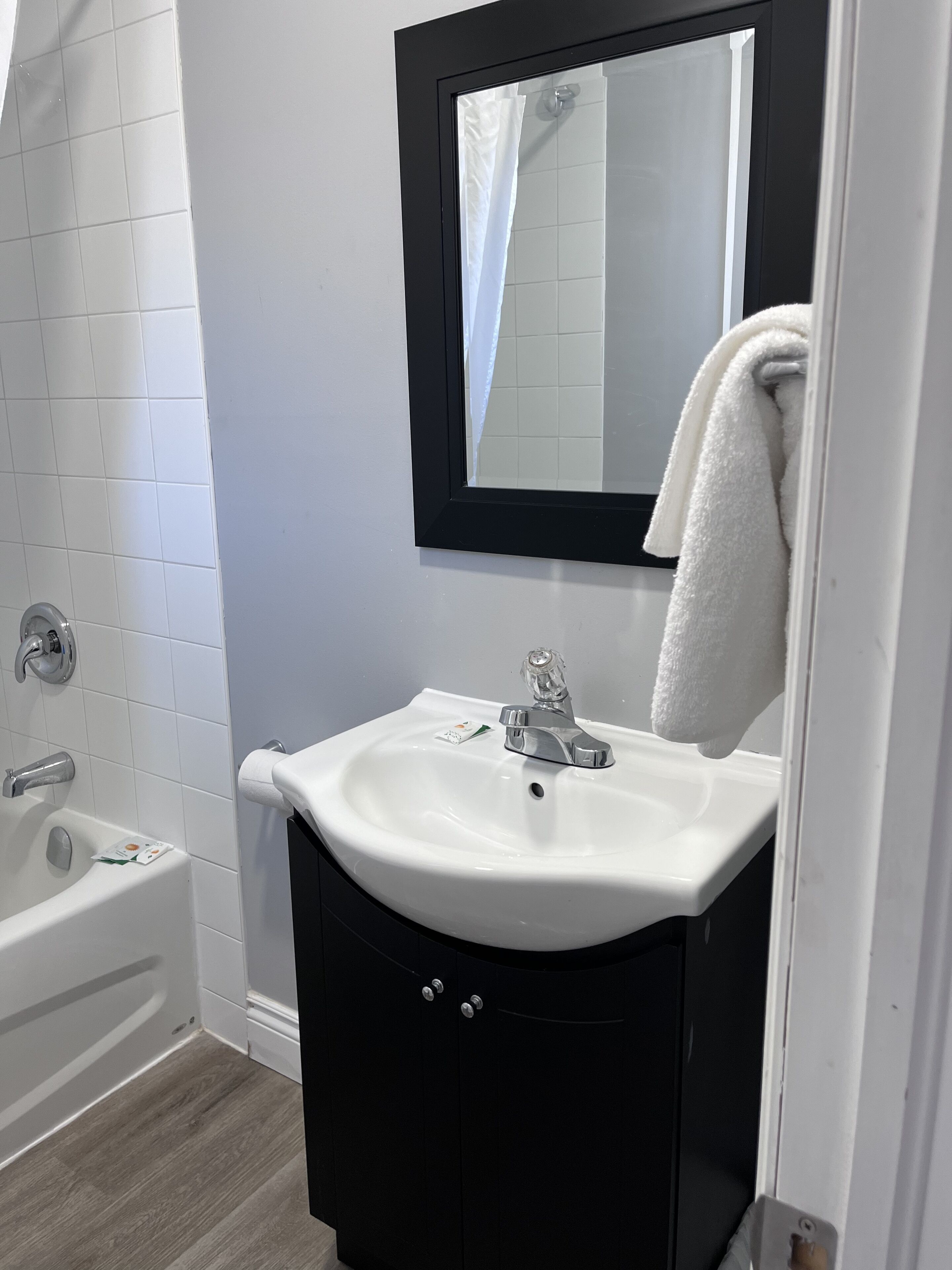 A bathroom with a white sink, black cabinet, and a mirror above the sink.