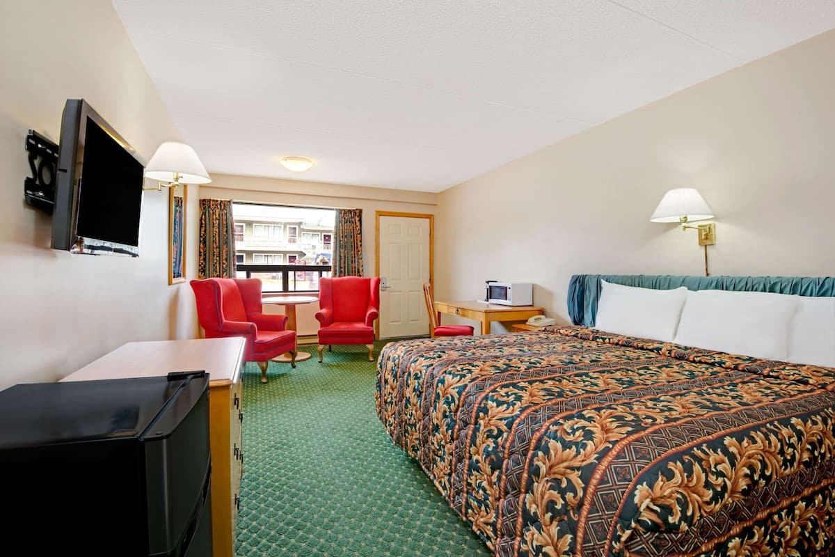 A hotel room with a bed, a desk, a TV, and a chair.