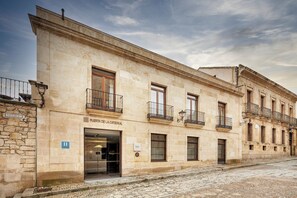 A historic building with a stone facade, multiple balconies, and a sign indicating it is the "Puerta de la Catedral."