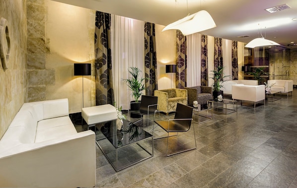 A modern lobby with a seating area, a reception desk, and a large chandelier.