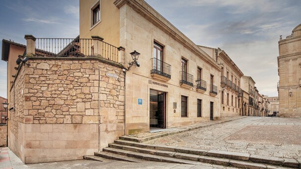 A historic building with a stone facade, multiple balconies, and a staircase leading to the entrance. - Sercotel Puerta de la Catedral (Salamanca)
