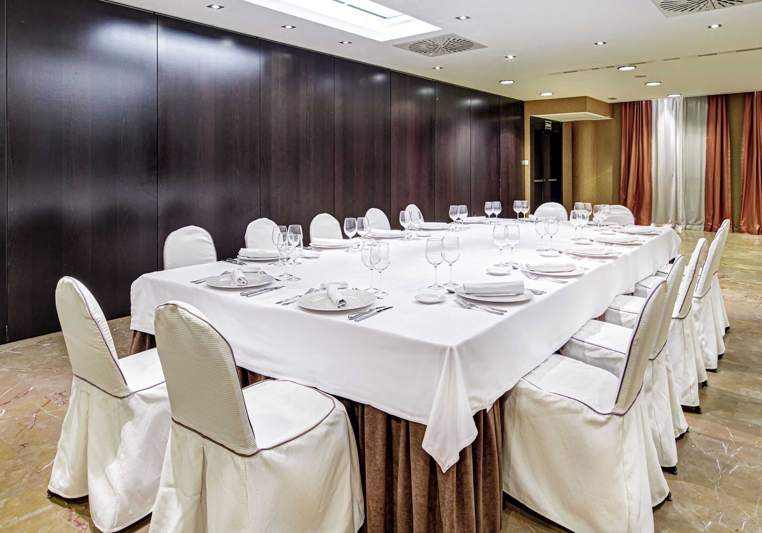 A conference room with a long table set for a meeting, surrounded by chairs.