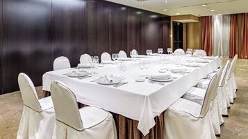 A conference room with a long table set for a meeting, surrounded by chairs.