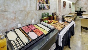 Een buffet met diverse gerechten, zoals vlees, kazen, fruit en groenten.