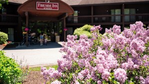 A Fireside Inn with a covered entrance, a bike rack, and blooming lilac bushes in the foreground.