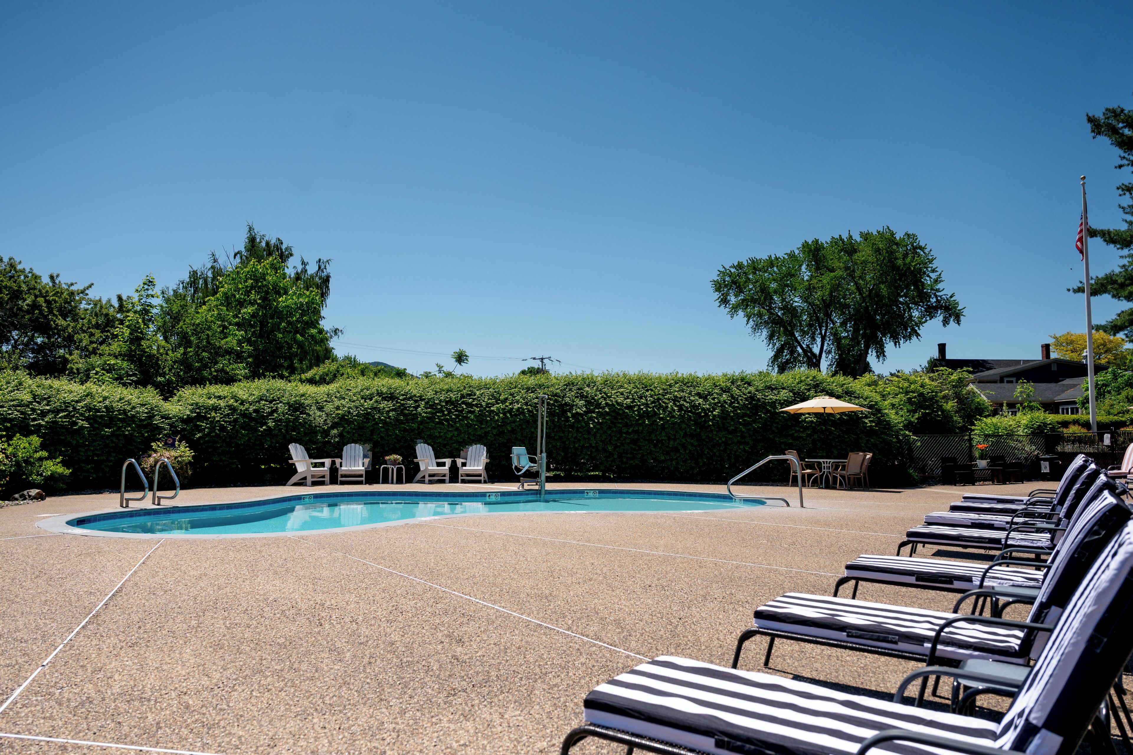 Une piscine avec des chaises longues et un mât pour drapeau.