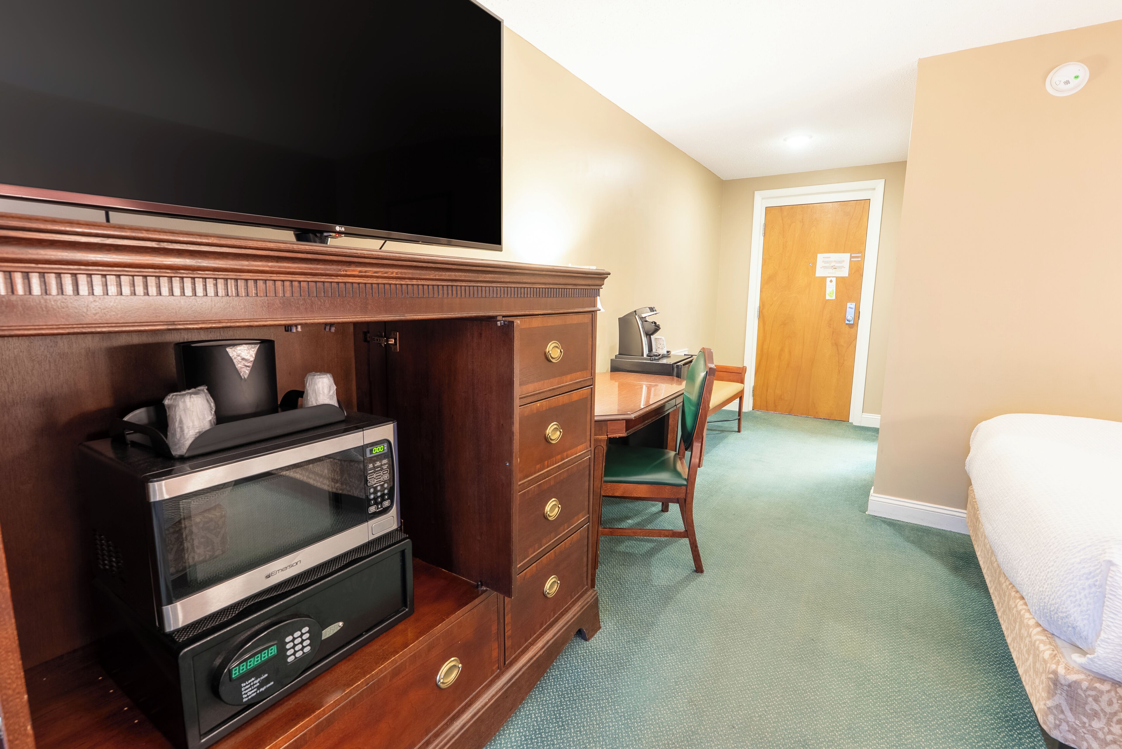 A hotel room with a microwave, a television, a desk, and a chair.