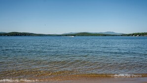 A calm lake with clear water, distant mountains, and a small boat.
