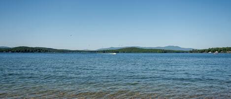 Ein ruhiger See mit klarem Wasser, fernen Bergen und einem kleinen Boot.