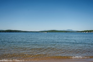 A calm lake with clear water, distant mountains, and a small boat.