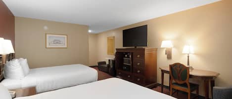Une chambre d’hôtel avec deux lits, une télévision, un bureau avec une chaise et une lampe.