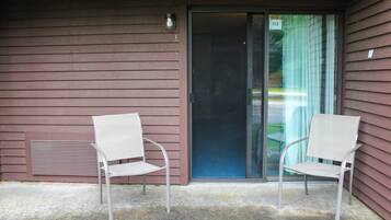 A building with two white chairs outside a sliding glass door.