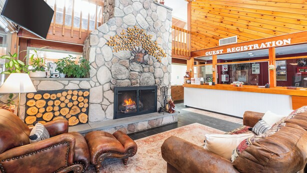 A lobby with a stone fireplace, leather sofas, a guest registration desk, and a television mounted on the wall.