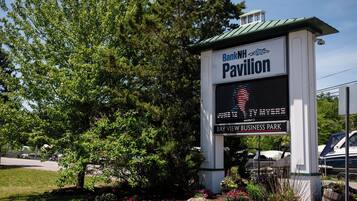 A sign for BankNH Pavilion with a digital display and a view of the Bay View Business Park.