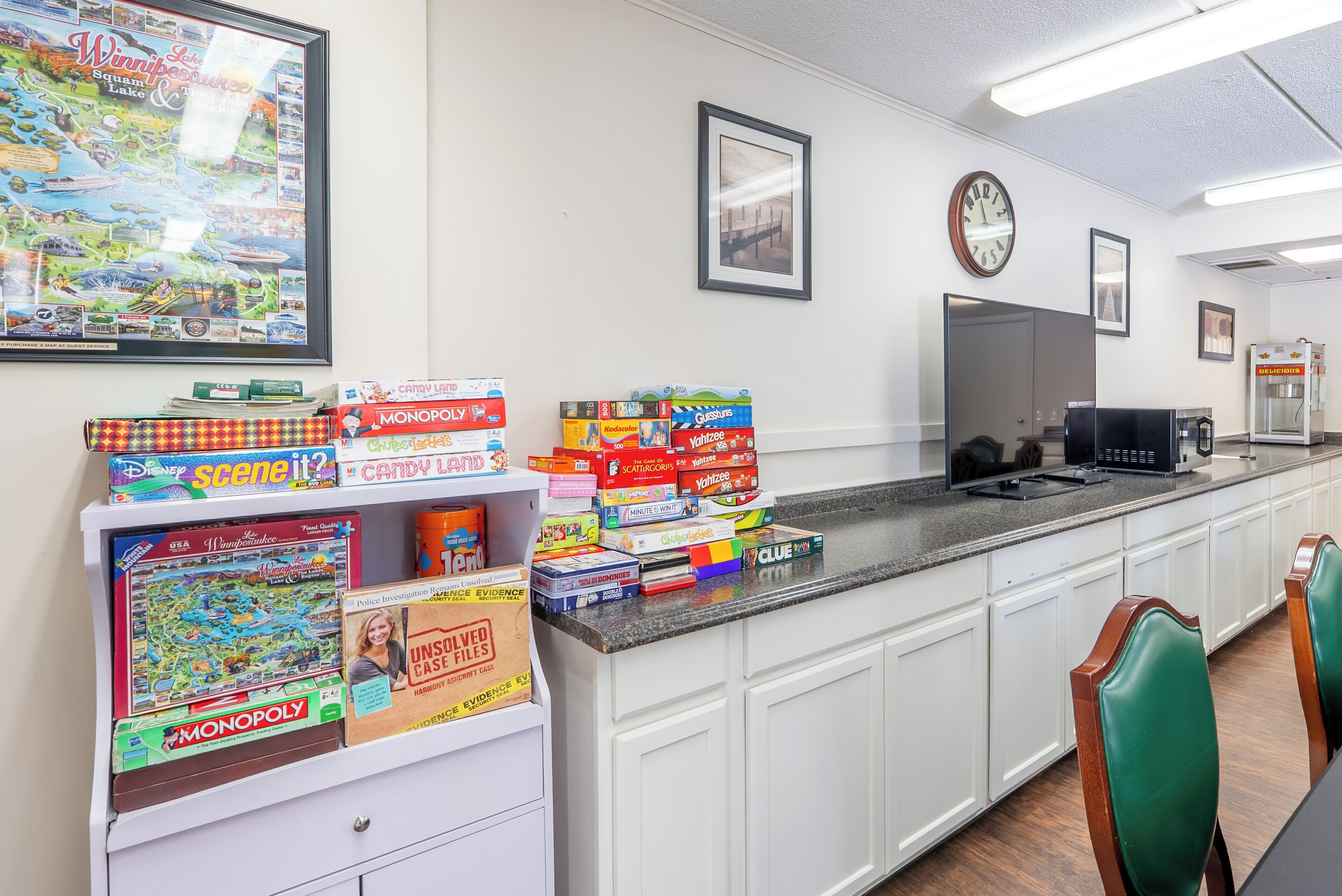 A kitchen area with a countertop displaying various board games, a clock, and a refrigerator.