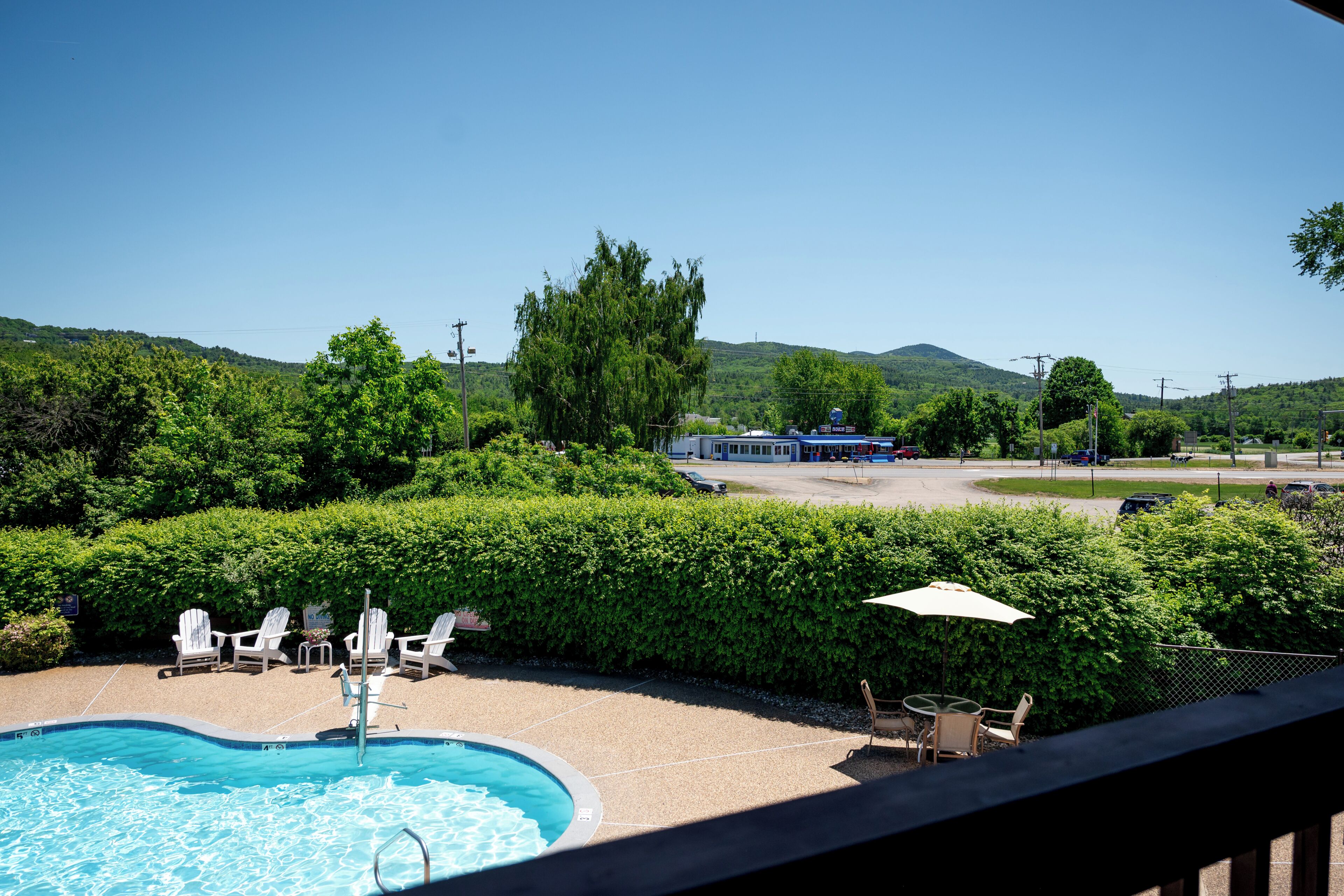 Una piscina con sedie a sdraio e un tavolo, circondata da vegetazione e colline.