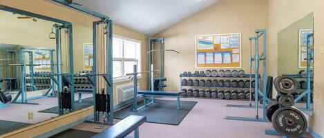 A gym with weightlifting equipment, benches, and dumbbells.