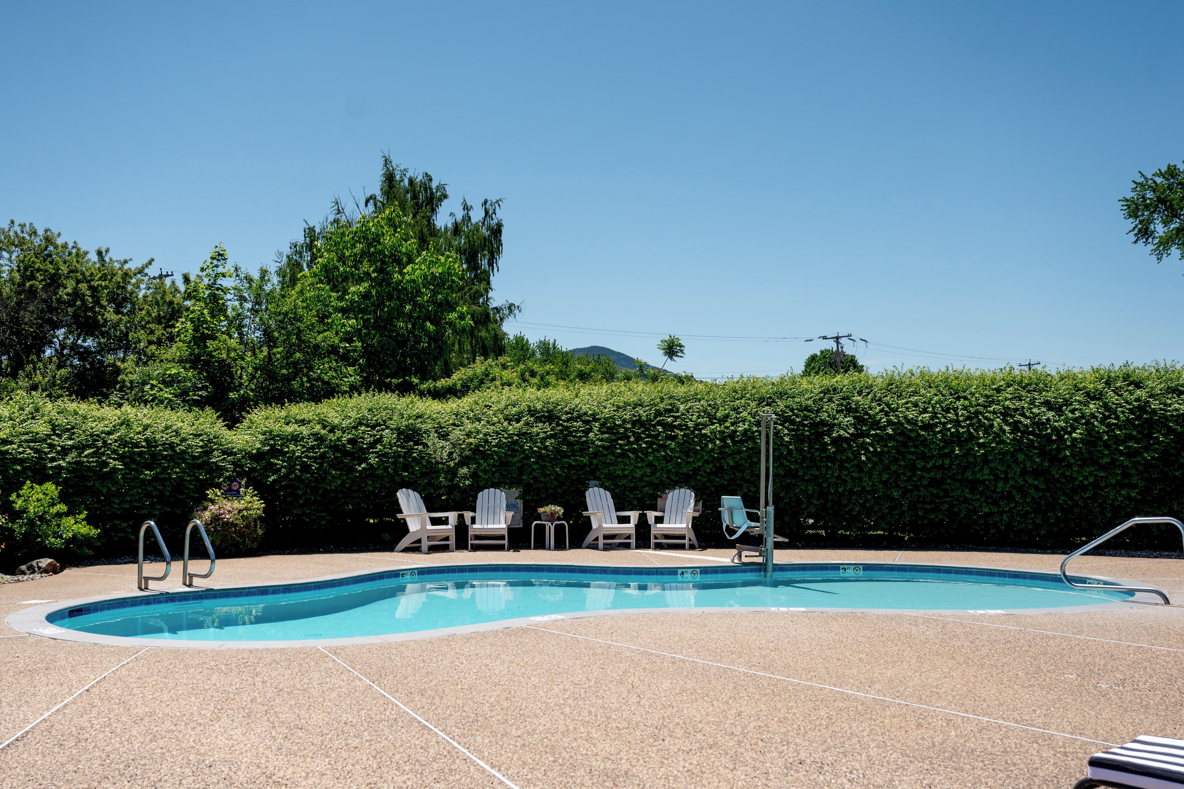 Une piscine avec des chaises longues et un escalier en métal.