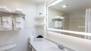 Un baño moderno con un espejo grande, toallas blancas en estantes, un lavabo y una zona de ducha.