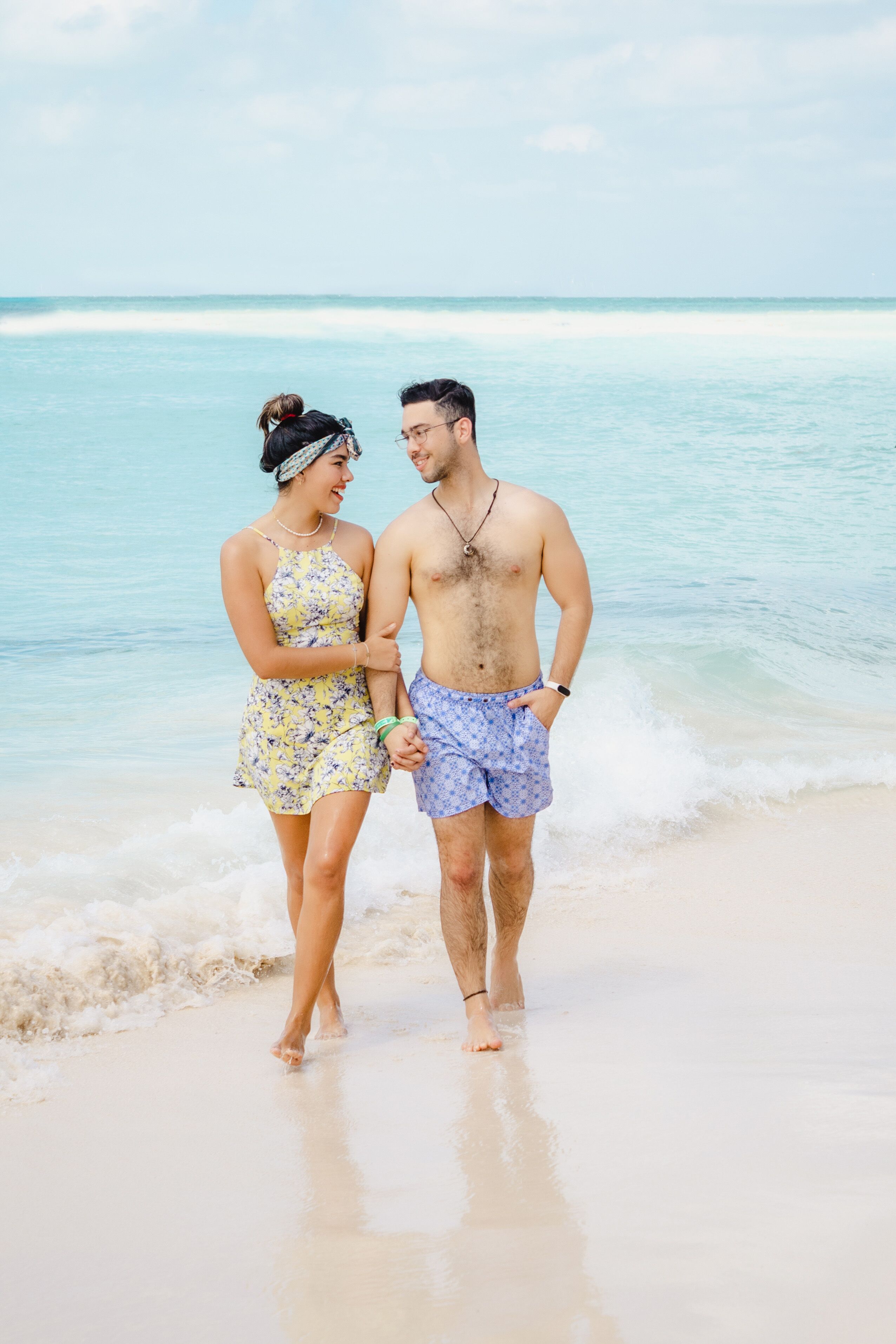 A couple standing on a beach with ocean waves in the background.
