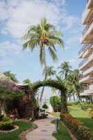 A pathway leading to a covered area with palm trees and a view of the ocean.