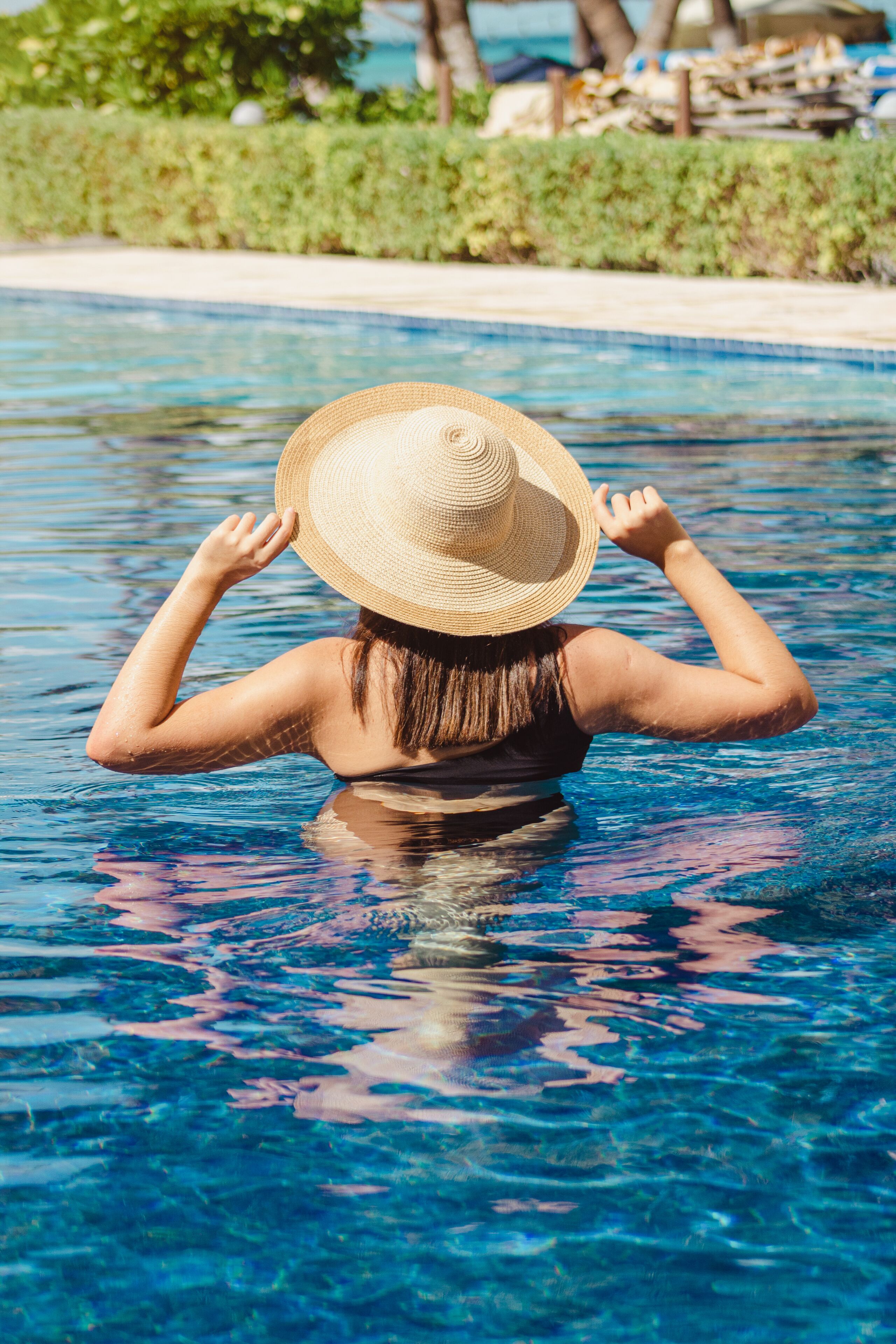 Eine Person trägt einen Strohhut und befindet sich in einem Schwimmbecken.