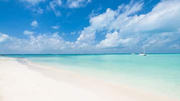 Na praia, areia branca, espreguiçadeiras, guarda-sóis
