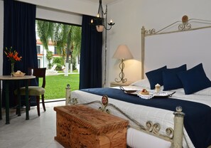 A hotel room with a bed, a desk with a chair, a lamp, and a view of the outdoors.