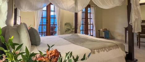 Ein Schlafzimmer mit Baldachinbett, großen Fenstern und Meerblick.