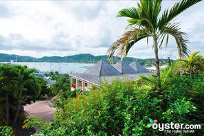 Ein Hotel mit pyramidenförmigem Dach, umgeben von üppiger Vegetation und Blick aufs Meer.