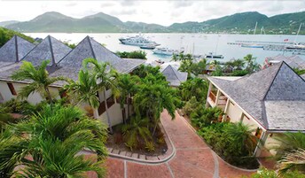 Un resort con varias edificaciones tipo bungalow, un paseo pavimentado y un puerto deportivo con barcos.
