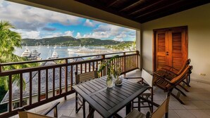 Un balcón con vista a un puerto deportivo, una mesa de madera, sillas y una puerta.