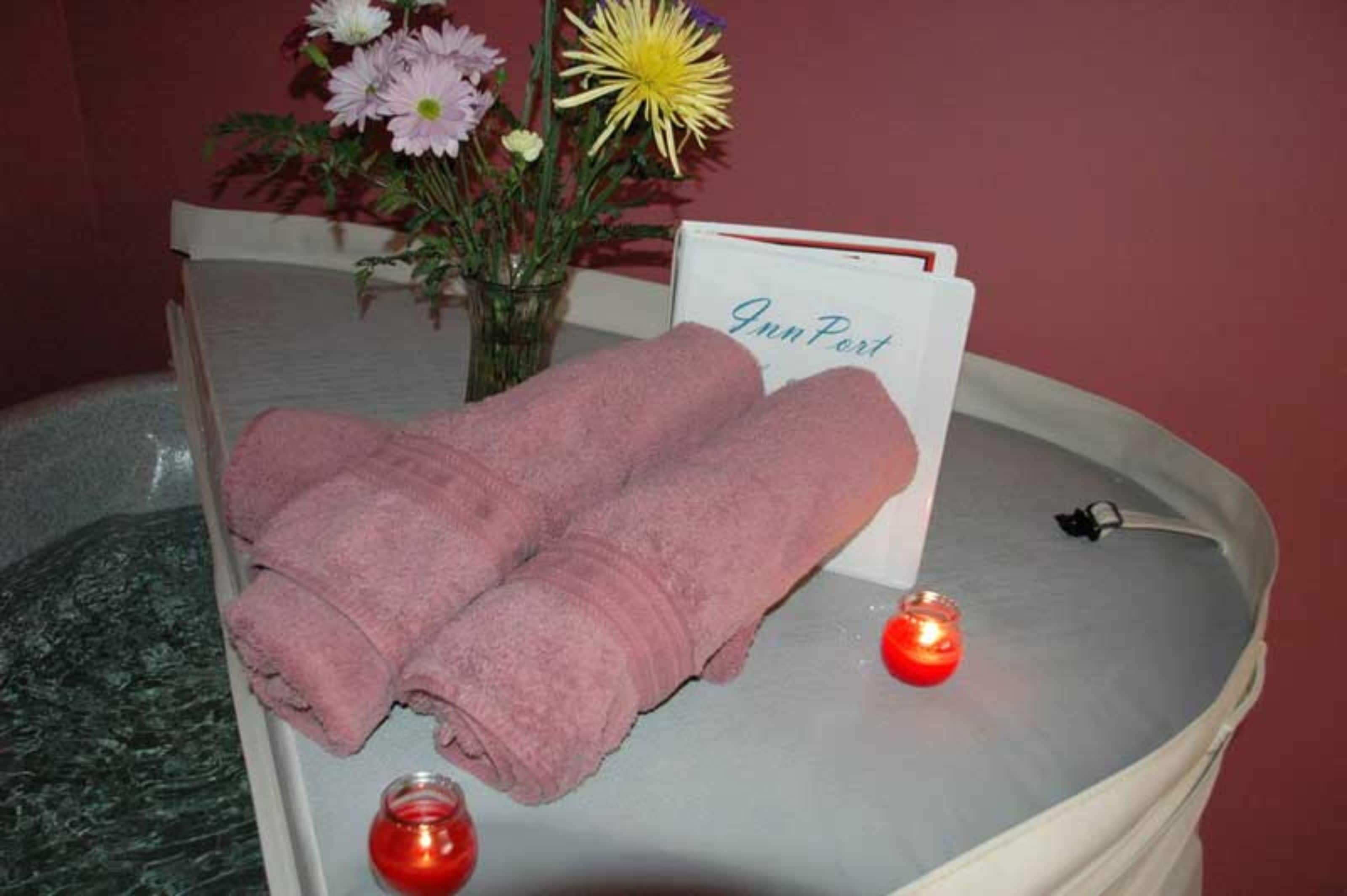 A spa tub with pink towels, a candle, and a card that reads "InnPort".