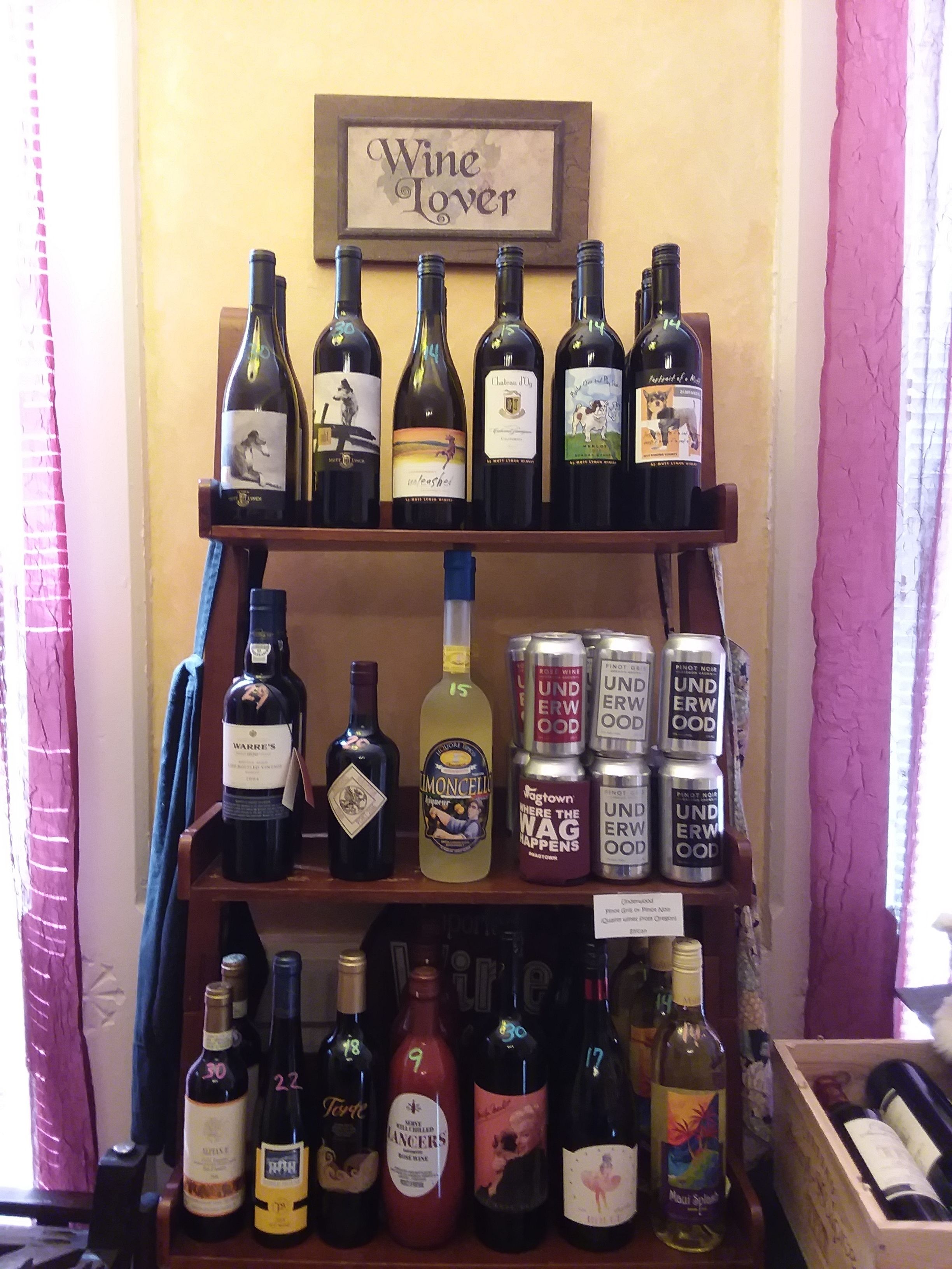 Uma adega com vários vinhos e latas, incluindo garrafas de vinho e bebidas enlatadas.