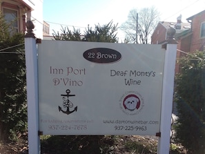 Une enseigne indiquant « Inn Port D’Vino » et « Deaf Monty’s Wine », avec les numéros de téléphone et l’adresse du site web.