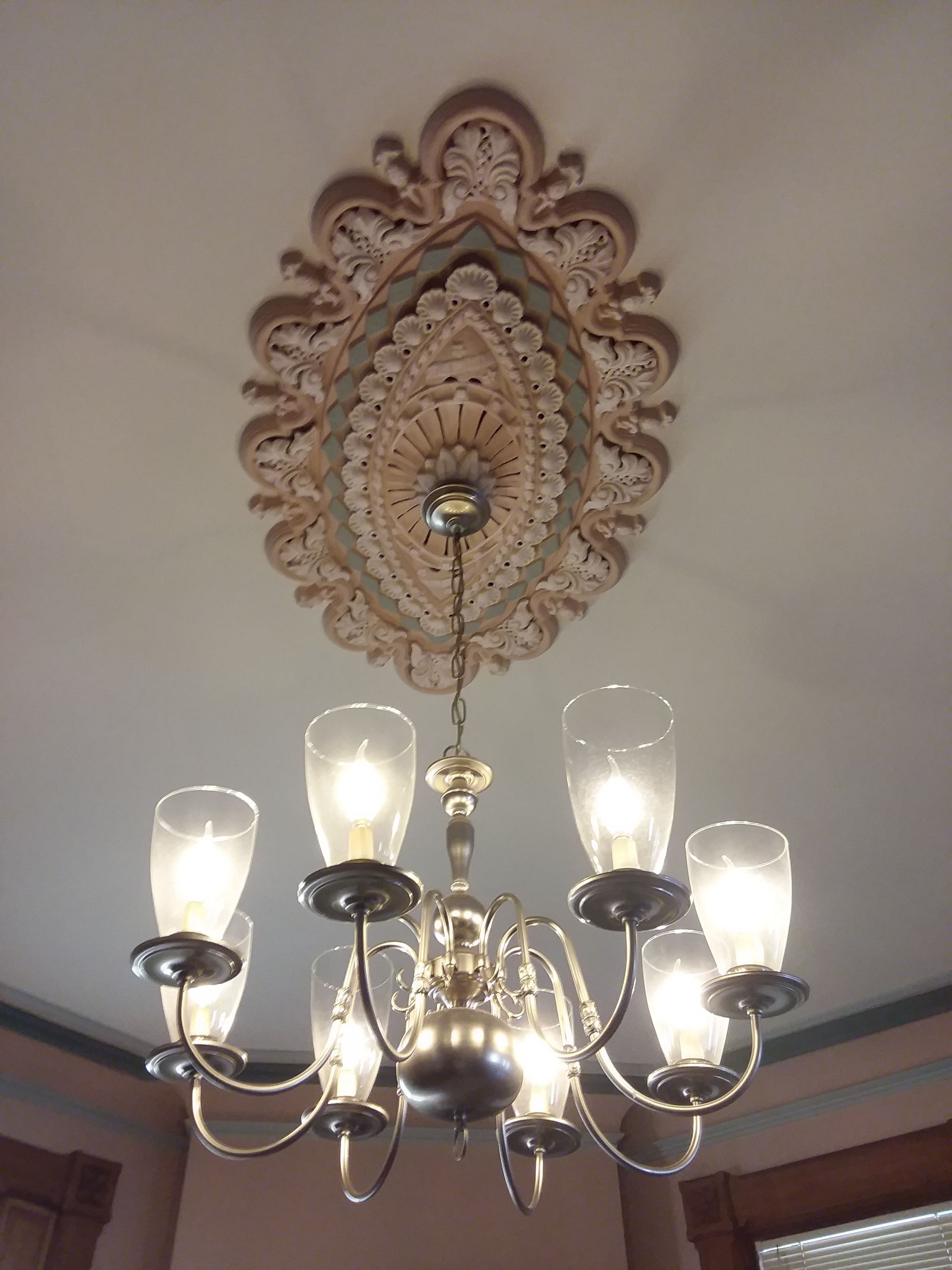A chandelier with multiple glass shades and a decorative ceiling medallion.