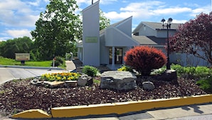 A lodge with a sign reading "Hawk's Nest Lodge" and a bird illustration. There is a well-maintained garden with flowers and rocks.