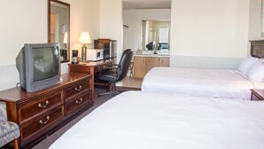 A hotel room with a television, desk, chair, two beds, and a mirror.