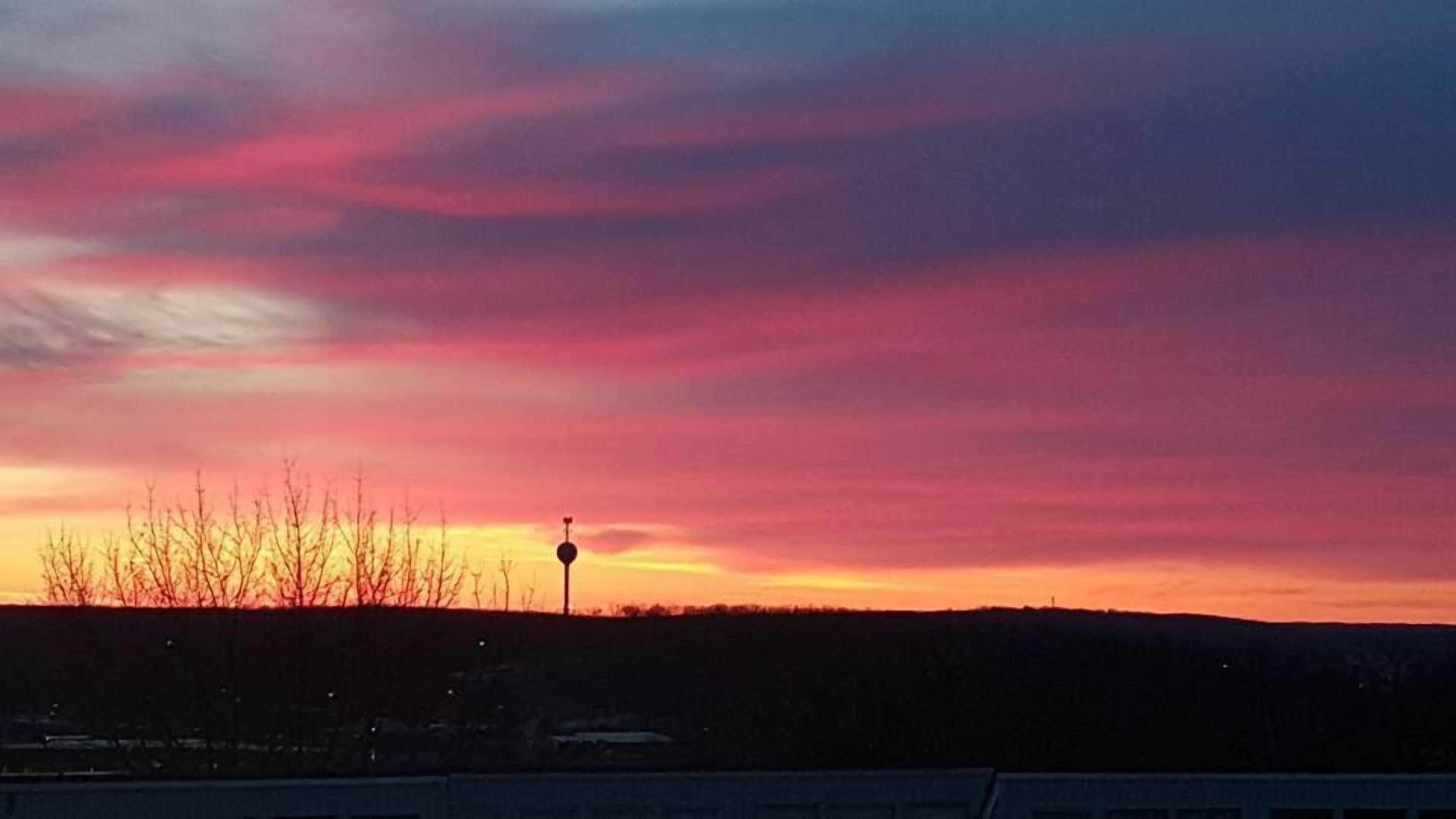 Un coucher de soleil avec un ciel dégagé et la silhouette d’un paysage.
