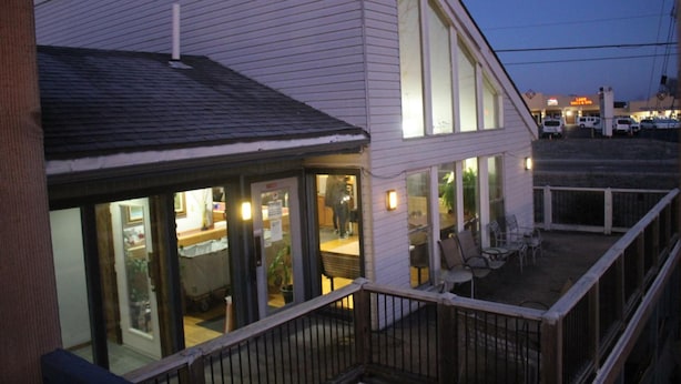 A two-story building with a balcony and a covered outdoor seating area.