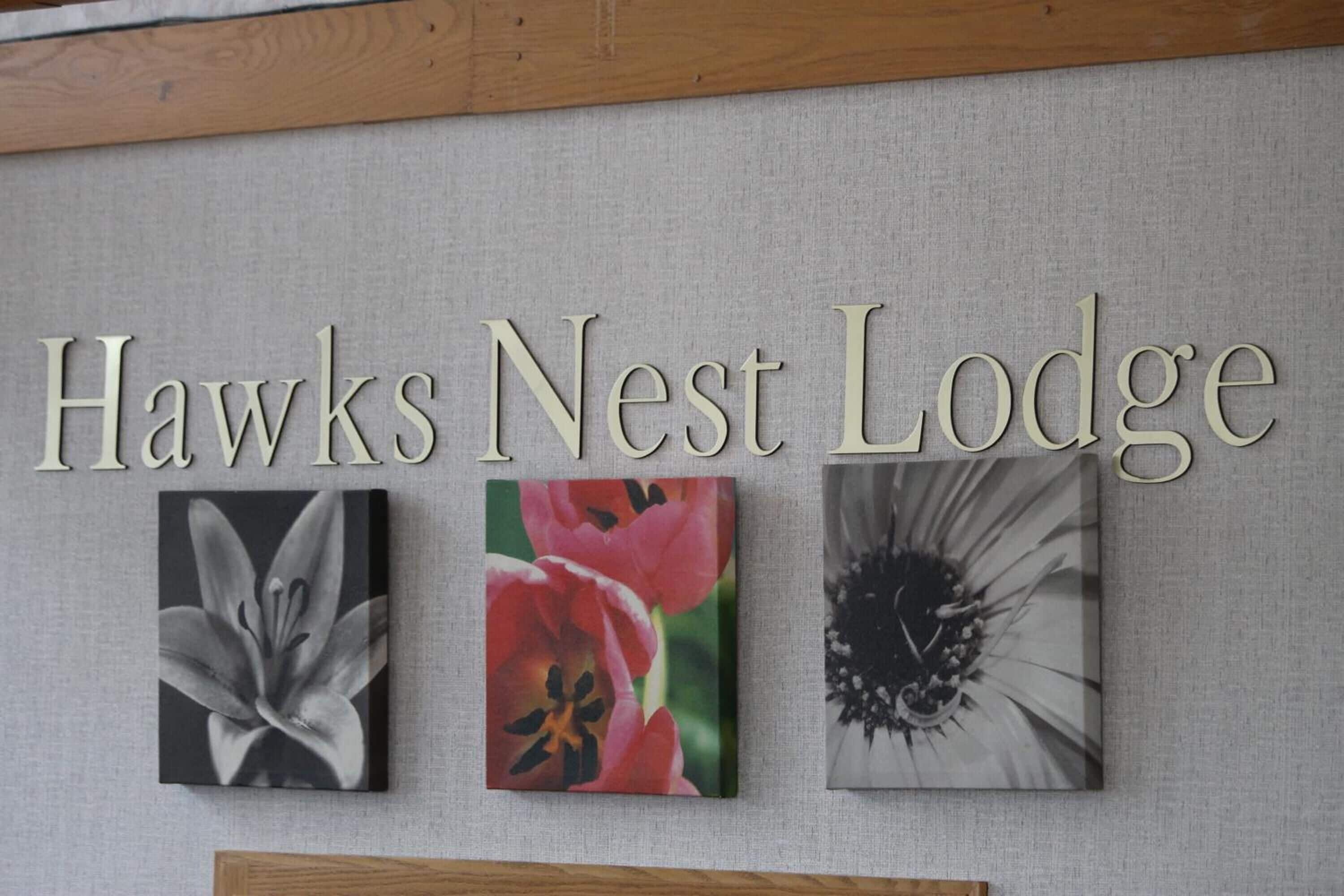 A wall with the text 'Hawks Nest Lodge' and three framed pictures of flowers.