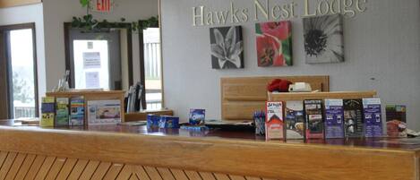 Un mostrador de recepción en Hawks Nest Lodge, con una barra de madera, folletos informativos y un cartel en la pared.